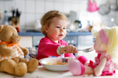 Çatal sebze ve makarna yemek bebek kız. Besleme ve oyuncak bebekle oynarken küçük çocuk