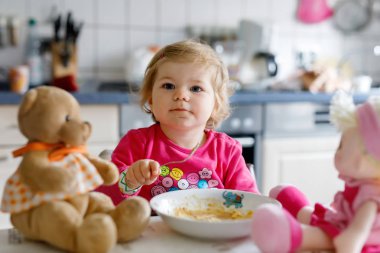Çatal sebze ve makarna yemek bebek kız. Besleme ve oyuncak bebekle oynarken küçük çocuk