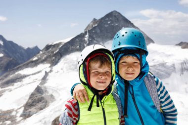 Emanet kask ve giyim dağlar manzara arka planlar ile iki küçük çocuklar. Yürüyüş ve Tirol, Avusturya, Hintertux buzul keşfetmek çocuklar