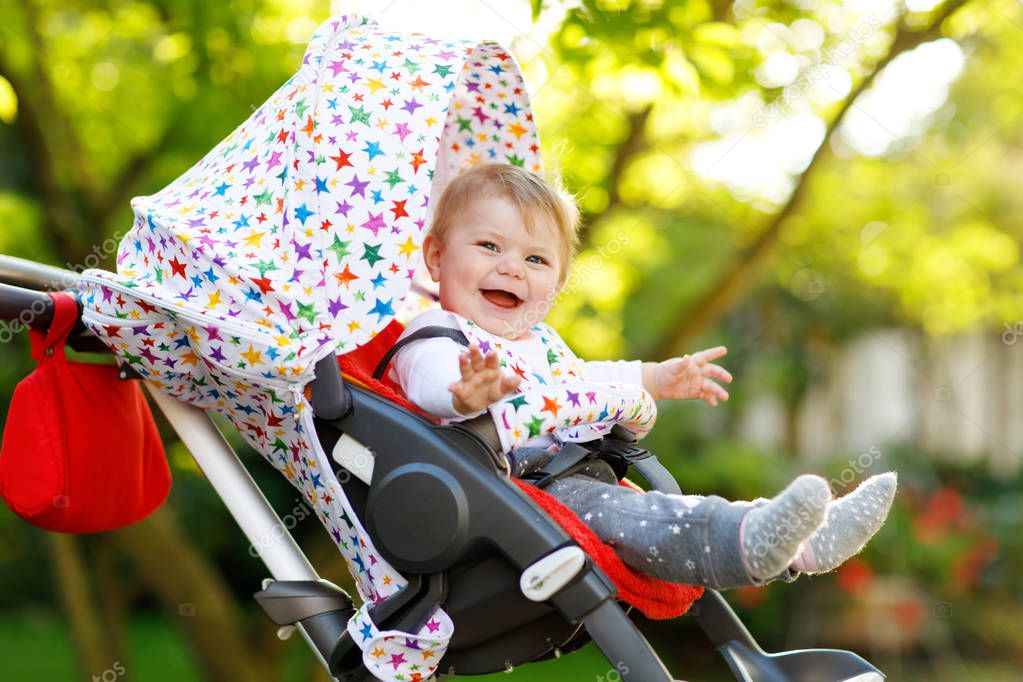 Cute little beautiful baby girl of 6 months sitting in the pram or stroller and waiting for mom