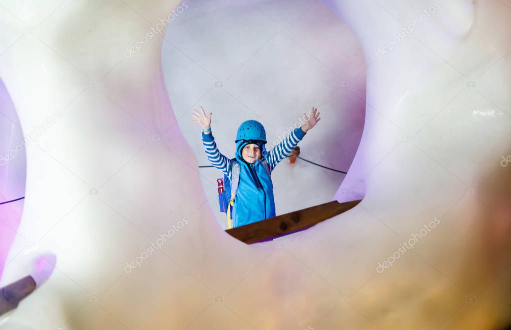 Little kid boy with safety helmets inside of glacier with ice tunnel. Schoolkid hiking and discovering mountain in Tirol, Austria, Hintertux.