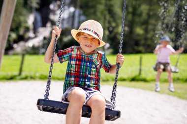 Komik çocuk çocuk iken ıslak olduğu su ile sıçrayan ile zincir salıncak açık sahada eğleniyor