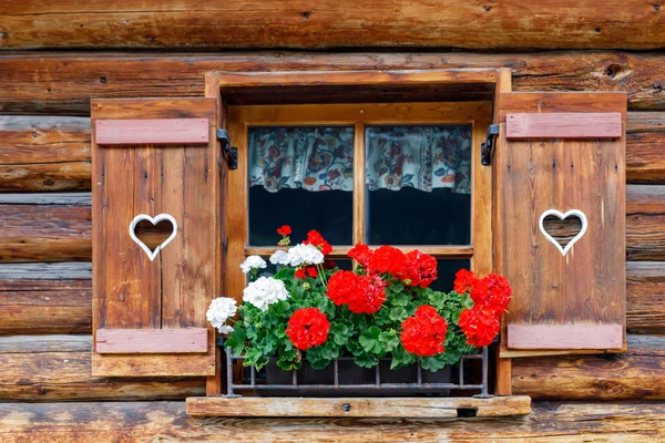 Typiska bayerska eller österrikiska trä fönster med röd pelargon blommor på hus i Österrike eller Tyskland — Stockfoto