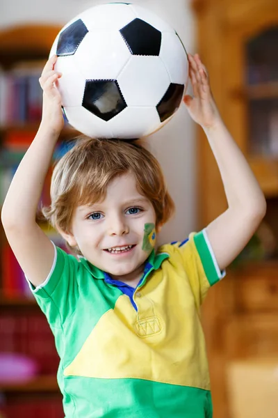 Little blond preschool kid boy with ball watching soccer football cup game on tv. — Stock Photo, Image