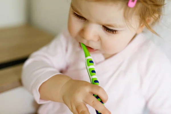 Niña sosteniendo cepillo de dientes y cepillándose los primeros dientes. Niños pequeños aprendiendo a limpiar los dientes de leche. — Foto de Stock