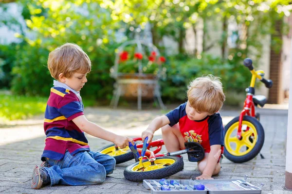Twee gelukkige kleine jongen jongens reparatie keten op fietsen en verandering wiel van evenwicht fiets — Stockfoto