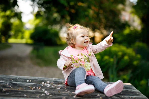 Leuk schattig peuter meisje speelt met bloeiende kastanje bloemen. Kindje van de baby gaan voor een wandeling op zonnige dag. — Stockfoto