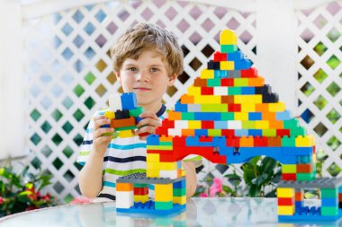 Küçük sarışın çocuk ve çocuk bir sürü renkli plastik blokla oynuyorlar..