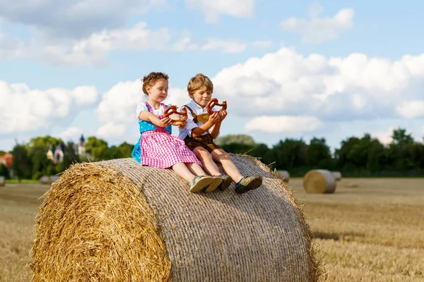 Two kids, boy and girl in traditional Bavarian costumes in wheat field — Stock Photo, Image