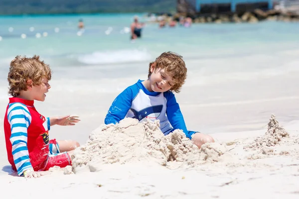 Due bambini piccoli ragazzi si divertono con la costruzione di un castello di sabbia sulla spiaggia tropicale dell'isola di carrube. — Foto Stock