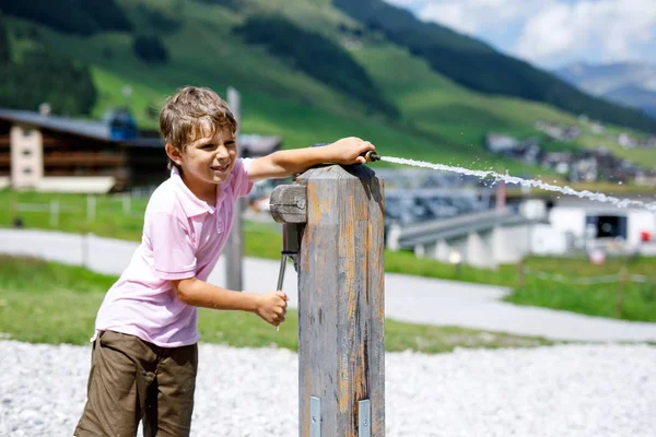 Kleine school jongen jongen spelen met waterpomp op een warme zomerdag — Stockfoto