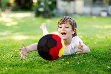 Aktif çocuk mutlu çocuk futbol topu Alman bayrağı renklerde oynamak. Sağlıklı çocuk futbol oyunu ve eylem açık havada ile eğleniyor