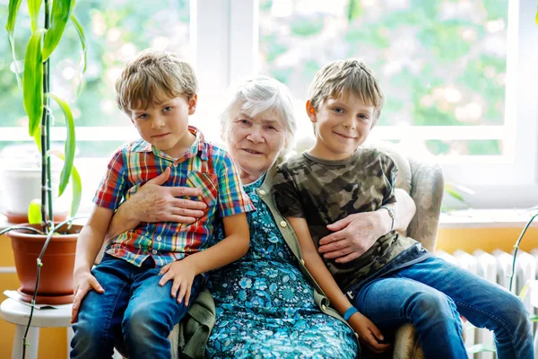 Happy family portrait with grandmother and two grandsons. Grand grandmother sitting with two school kid boys at home — Stock Photo, Image