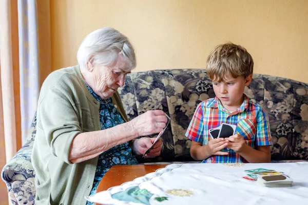 Active little preschool kid boy and grand grandmother playing card game together at home — Stock Photo, Image