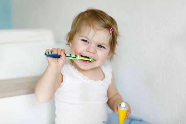 Niña sosteniendo cepillo de dientes y cepillándose los primeros dientes. Niños pequeños aprendiendo a limpiar los dientes de leche. — Foto de Stock