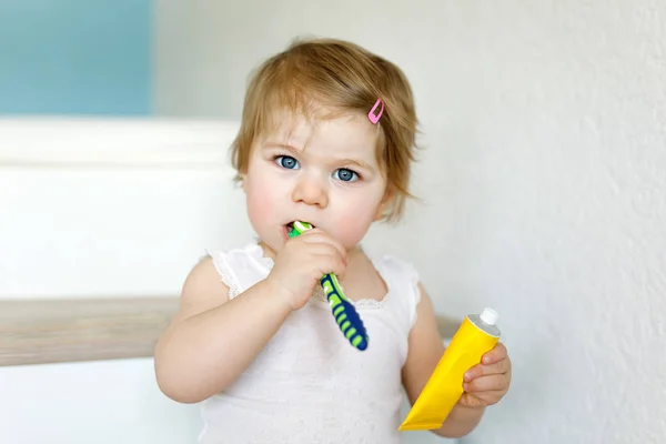 Niña sosteniendo cepillo de dientes y cepillándose los primeros dientes. Niños pequeños aprendiendo a limpiar los dientes de leche. — Foto de Stock