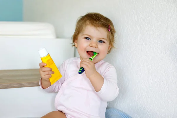 En liten flicka som håller i tandborsten och borstar tänderna. Småbarn lära sig att rengöra mjölk tand. — Stockfoto