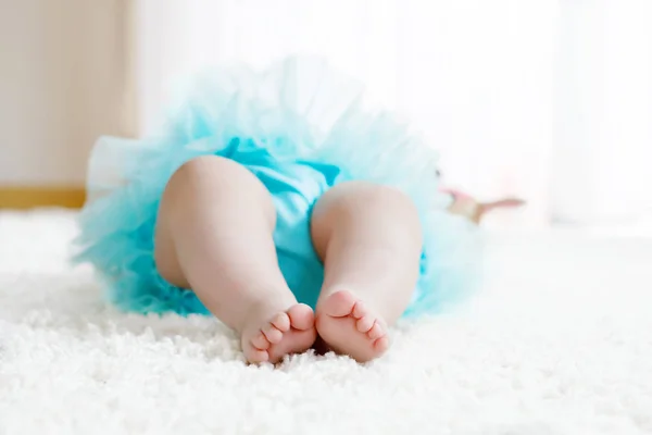 Närbild på ben och fötter med baby girl på vit bakgrund bär turkos tutu kjol. — Stockfoto