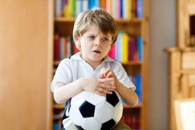 Futbolu ya da futbol maçını kaybettiği için üzgün ve mutsuz küçük bir çocuk. TV 'de maç izledikten sonra çocuk