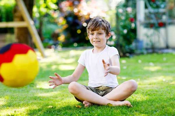 Aktif çocuk mutlu çocuk futbol topu Alman bayrağı renklerde oynamak. Sağlıklı çocuk futbol oyunu ve eylem açık havada ile eğleniyor