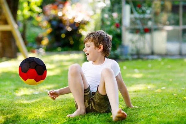 Gelukkig actieve jongen jongen te voetballen met bal in Duitse vlag kleuren. Gezond kind plezier met voetbal spel en actie outdoors — Stockfoto