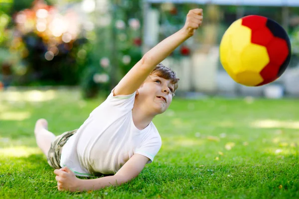 Glada aktiva barn pojke spela fotboll med boll i tysk flagg färger. Friskt barn ha roligt med fotboll spel och åtgärder utomhus — Stockfoto