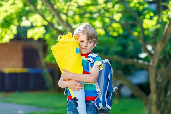 Liten unge pojke med skola skolväska på första dagen i skolan, håller skolan kon med gåvor — Stockfoto