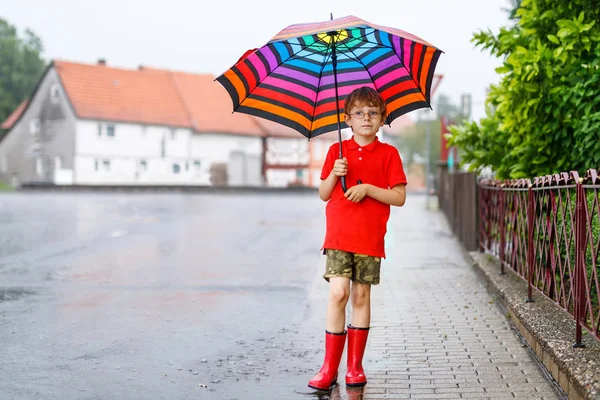 Ragazzo che indossa stivali da pioggia rossi e cammina con ombrello — Foto Stock