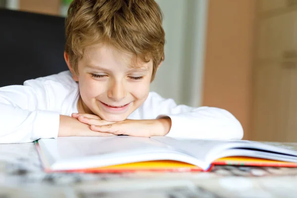 Petite écolière blonde garçon lisant un livre à la maison — Photo