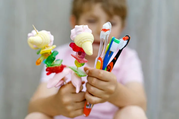 Beetje kid jongen holding marshmallow Spies in de ene hand en tandenborstels in een andere — Stockfoto