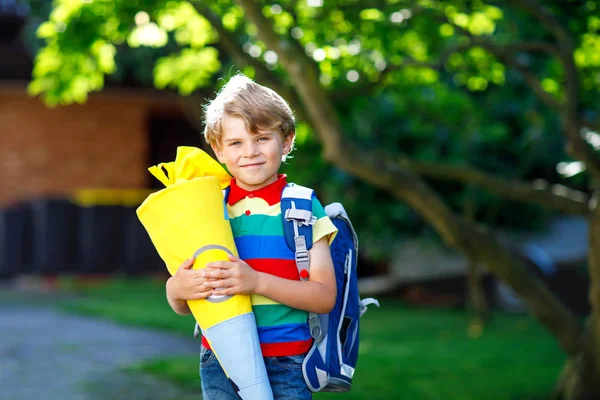 Маленький хлопчик з шкільним сателітом на перший день до школи, тримає шкільний конус з подарунками — стокове фото