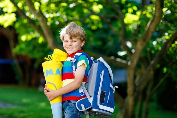 Маленький мальчик со школьной сумкой в первый день в школу, держа школьный конус с подарками — стоковое фото