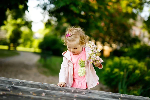 Söt bedårande barn girl spelar med blommande kastanj blommor. Lilla baby barn gå på en promenad på solig dag. — Stockfoto