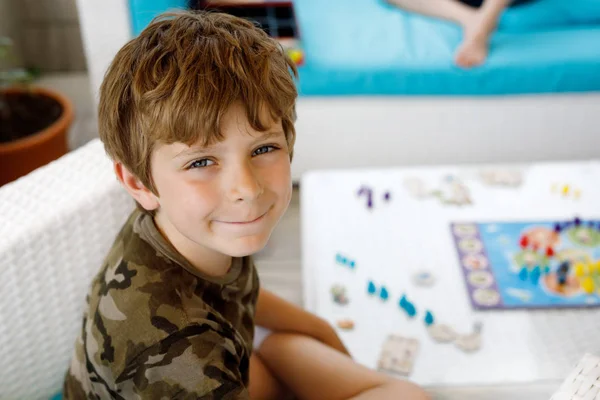 Little adorable school kid boy playing board game with family. Schoolkid and child having fun with active game.