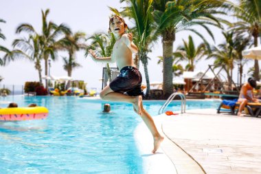 Havuza atlama ve eğlenmek aile tatil otel beldesinde mutlu küçük çocuk çocuk. Suda oynayan sağlıklı çocuk