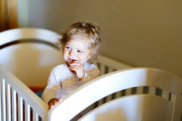 Schattig klein babymeisje liggend in bedje na het slapen. Gezond gelukkig kind in bed klimmen uit. — Stockfoto