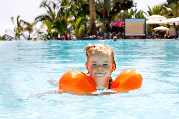 Linda niña feliz nadando en la piscina y divirtiéndose en vacaciones familiares en un complejo hotelero. Niño sano jugando en el agua . — Foto de Stock