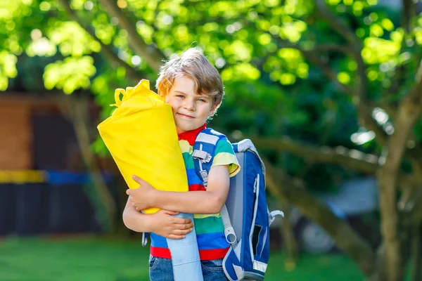 Little kid boy with school satchel on first day to school, holding school cone with gifts — Stock Photo, Image