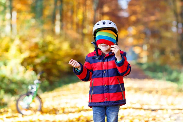 Actief kind zet veilige helm voordat fietsen op zonnige herfstdag in de natuur. — Stockfoto