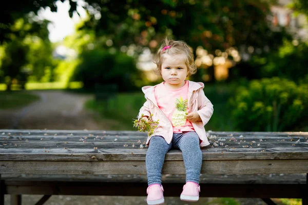 Leuk schattig peuter meisje speelt met bloeiende kastanje bloemen. Kindje van de baby gaan voor een wandeling op zonnige dag. — Stockfoto