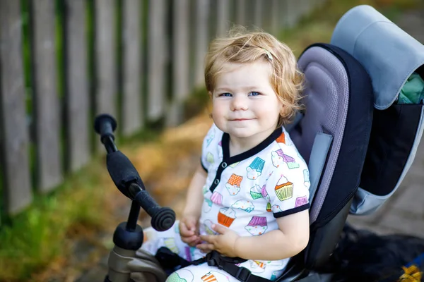 Linda niña adorable niño sentado en bicicleta empujando o triciclo. Niño pequeño que va a dar un paseo con sus padres en un día soleado. — Foto de Stock