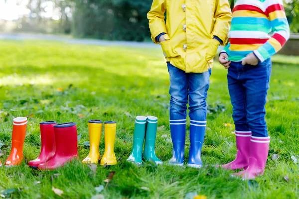 Niños pequeños, niños o niñas en jeans y chaqueta amarilla en botas de lluvia coloridas — Foto de Stock