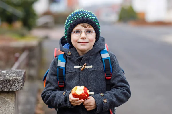 Little kid boy with eye glasses walking from the school and eating apple — Stock Photo, Image