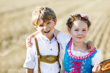 Buğday tarlasında geleneksel Bavyera kostümlü iki çocuk.