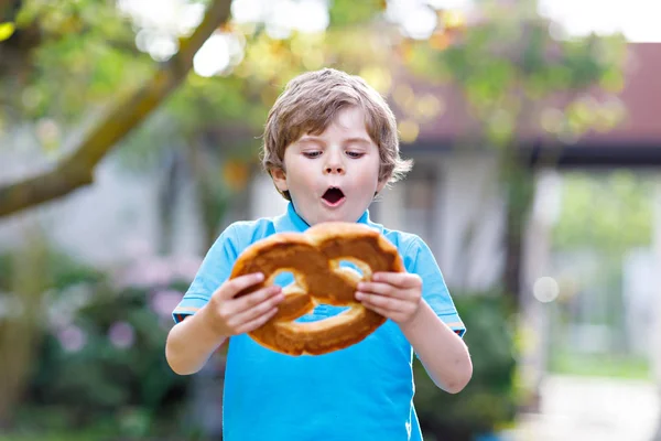 愛らしい子供の男の子は巨大な大規模な野蛮ドイツ語のプレッツェルを食べる 伝統的なパンを楽しむ幸せな金髪の子供 幸せな子供のための健康食品 — ストック写真