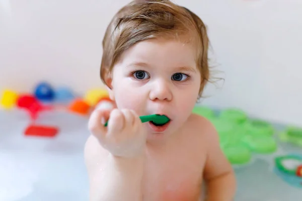 Linda menina adorável tomando banho espumoso na banheira. Criança brincando com brinquedos de borracha de banho. — Fotografia de Stock