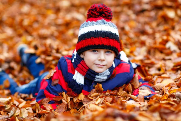 Schattig kleine jongen op herfst bladeren achtergrond in park. — Stockfoto