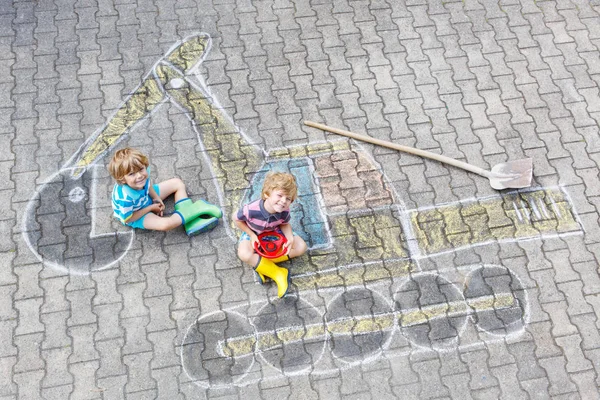 Два маленьких мальчика с картинкой из мела на экскаваторе — стоковое фото