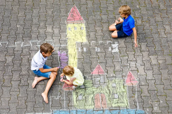 Två barn lite pojkar ritning knight slott med färgglada kritor på asfalt. Glada syskon och vänner att ha kul med att skapa krita bild och måleri. Kreativ fritid för barn i sommar. — Stockfoto