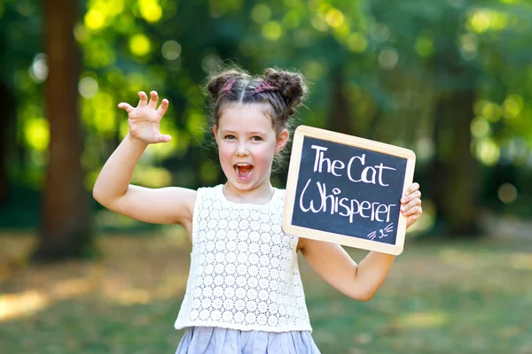 Niña feliz sosteniendo el escritorio de tiza vacío en las manos. Colegial en el primer día de clase elemental. Niño sano y adorable al aire libre, en el parque verde. profesión de sueño —  Fotos de Stock